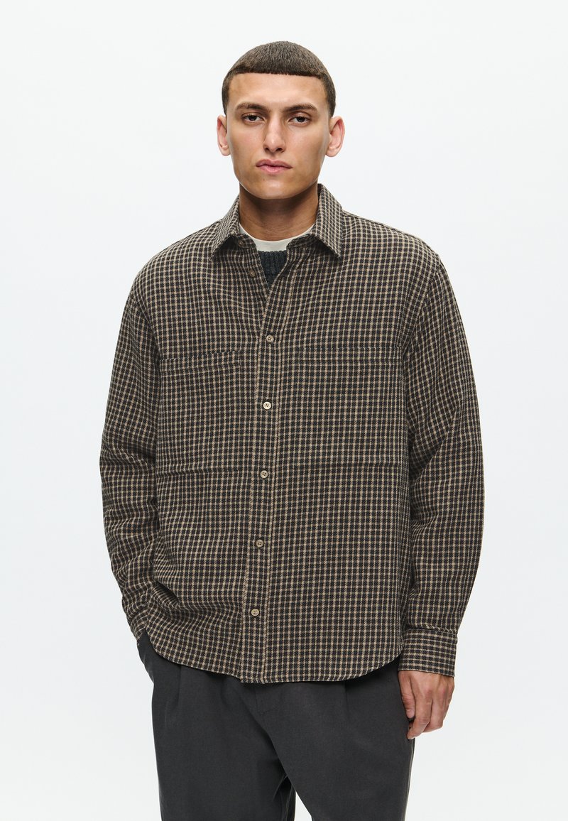 Barna és krémszínű kockás, gombos ing, terjedelmes gallérral és két mellzsebbel, puha, textúrált anyagból készült.