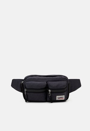 Bolsa de cintura negra compacta con dos bolsillos frontales con cremallera y correa ajustable, con un parche con el logo de Tommy Jeans.