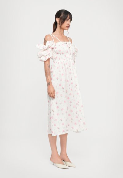 Hvid midi kjole med pink blomsterprint, pufærmer og smocket liv. Sammen med spidse, crèmefarvede mules.