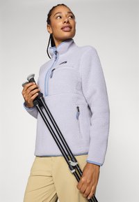 Lichtpaarse fleece trui met een hoge kraag, een halve rits en een borstzak. Voorzien van wandels Stokken, een soepele textuur met contrasterende blauwe accenten.