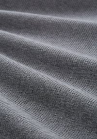 Szara tkanina o prążkowanej fakturze, ukazująca miękkie fałdy i subtelną poświatę. Zbliżenie podkreśla wzór i szczegóły materiału.