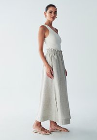 Light gray linen maxi skirt with a gathered elastic waistband, paired with a fitted white ribbed tank top and minimalist flat sandals.