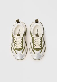 Baskets avec une tige en maille argentée ornée d'accents vert olive, de lacets crème et d'une semelle blanche texturée. Détails réfléchissants sur toute la chaussure.