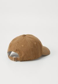 Casquette en coton marron avec une visière incurvée, sangle ajustable à l'arrière, et des détails cousus sur la couronne et la visière.