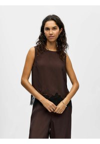 Top marrone senza maniche con orlo scallopato e dettagli in pizzo nero lungo il fondo. Tessuto liscio e vestibilità comoda.