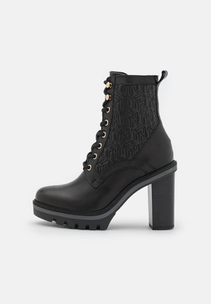 Bottine noire en cuir à talon haut avec lacets à l'avant, motif géométrique embossé sur le côté et semelle épaisse à crampons.