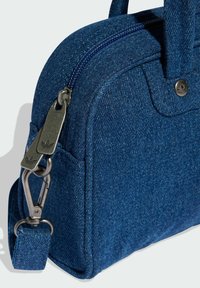 Mörkblå denimhandväska med en strukturerad form. Har dragkedjeförslutning och metallaccentdetaljer, inklusive ett nyckelringfäste.