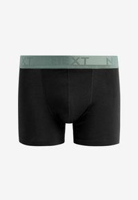 Schwarze Boxer aus weichem Stoff, mit einem hellgrünen elastischen Bund, auf dem das "NEXT"-Logo deutlich sichtbar ist.