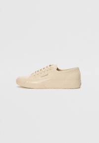 Beige lavsko sneakers med blank finish, med en teksturert gummisåle, rund tå og seks øyehull for snøring.