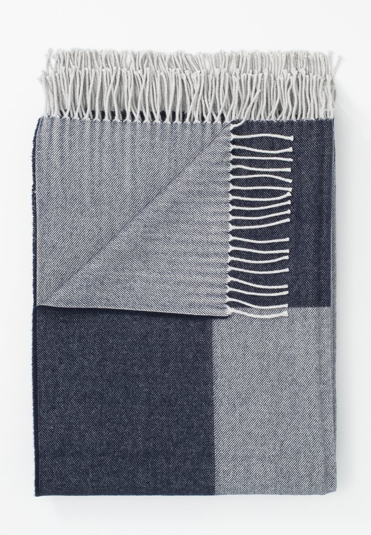 Gewebte Decke in Navy und Grau mit einem geometrischen Muster. Verfügt über fransige Kanten und eine weiche, strukturierte Oberfläche.