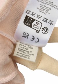 Beżowa metka tekstylna z instrukcjami pielęgnacji i danymi producenta, zawierająca logo oraz ikony dotyczące prania, suszenia i prasowania.