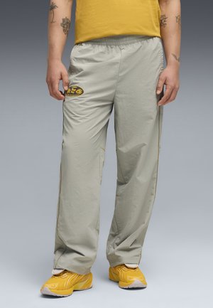 Jasnoszare spodnie sportowe z elastycznym paskiem, bocznymi akcentami w kolorze żółtym oraz czarnym okrągłym logo na lewym udzie.