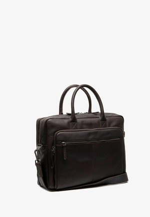 Mallette en cuir marron foncé avec double poignée, poche avant zippée et bandoulière amovible sur fond blanc.