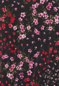 Schwarzer Stoff, der mit einem Blumenmuster bedeckt ist, das Gruppen von rosa und roten Blumen mit grünen Blättern zeigt und verschiedene Formen und Größen aufweist.