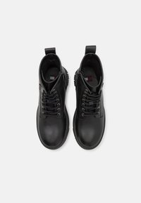 Bottines en cuir noir à lacets, bout rond, semelle en caoutchouc et languette à l'arrière. L'intérieur est doux avec une semelle intérieure texturée.