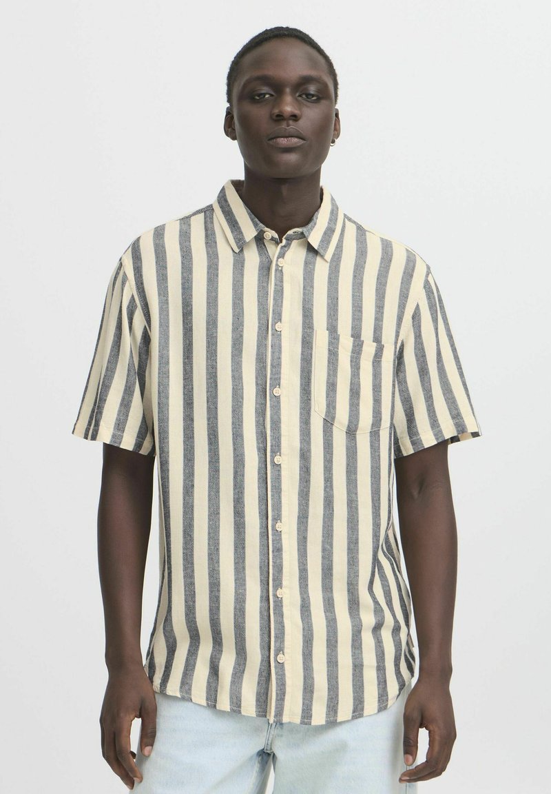 Camicia a maniche corte con righe verticali blu navy e crema, aperture con bottoni, colletto a punta e taschino sul petto. Realizzata in tessuto testurizzato.