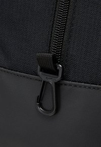 Black fabric bag with a textured surface, featuring a zipper and a black plastic carabiner clip. Smooth matte finish with sturdy stitching.