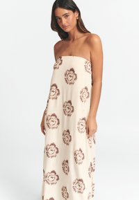 Rihmatu rakendusevaba kreemjas maxi kleit pruunide lillemustritega, millel on mugav lõige ja pehme tekstuur, sobib igapäevaseks kandmiseks.