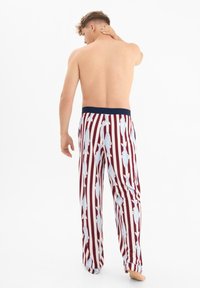 Rood-witte gestreepte pyjamabroek met blauwe vissenpatronen. Elastieke marineblauwe tailleband. Lichtgewicht stof, losse pasvorm.