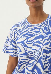 T-shirt à manches courtes bleu et blanc avec un motif rayé zèbre, fabriqué en coton doux, avec un col rond et une coupe décontractée.