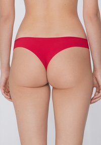 Rote Bikini-Hosen aus glattem Stoff, mit einem tiefen Schnitt und minimaler Rückendeckung, abgerundeten Kanten und ohne sichtbare Nähte.