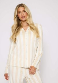 Kariertes Pyjama-Set aus weichem Material, mit beigen und weißen vertikalen Streifen, durchgehender Knopfleiste und einer Brusttasche.