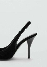 Černé lodičky na podpatku typu slingback s špičatou špičkou, hladkým sametovým povrchem a štíhlým jehlovým podpatkem.