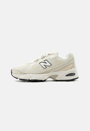 Chaussure de course New Balance blanche et beige avec semelle noire et logo, empeigne en mesh et amorti ABZORB sur fond uni.