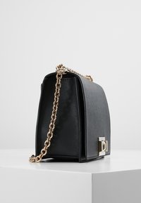 Borsa a mano in pelle nera con forma strutturata, tracolla in catena dorata e un dettaglio di chiusura prominente. Finitura testurizzata all'esterno.