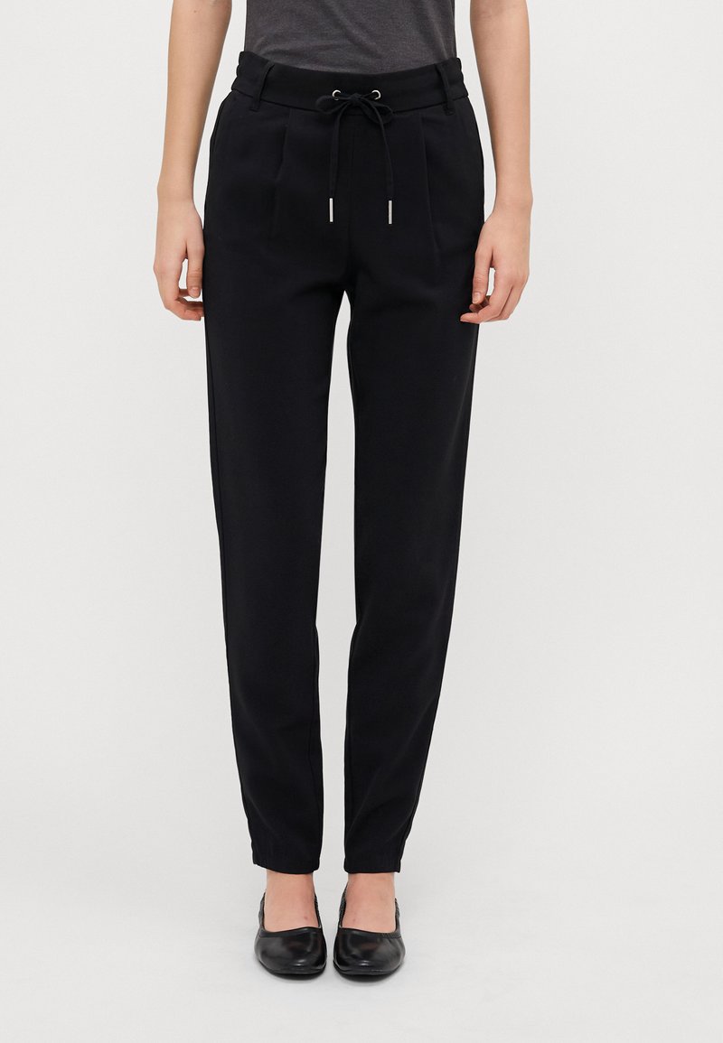 Pantalons noirs fuselés avec une taille élastique, fermeture à cordon de serrage, deux poches avant et chevilles côtelées. Texture de tissu lisse.