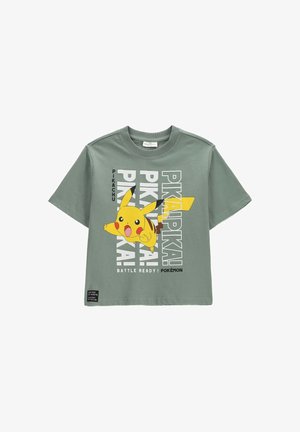 Zielona koszulka z krótkim rękawem z dużą grafiką Pikachu i powtarzającym się tekstem "PIKA PIKA", oraz "BATTLE READY! POKÉMON" na dole.