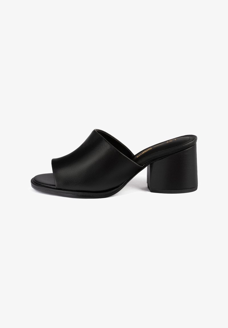 Mules à talons noirs en cuir lisse avec un design ouvert à l'avant et un talon bloc épais pour la stabilité. Surface texturée avec un minimum de détails.