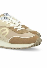 Beige en tan sneakers van suede en stof, met platte witte veters, een gestructureerde zool en een logodetail aan de zijkant.