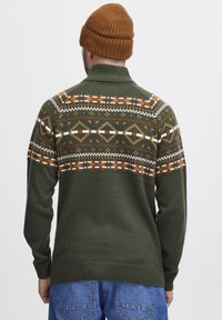 Pulover din lână Kwik, de culoare verde închis, cu guler înalt. Prezintă un yoke cu inspirație în modele de culoare maronie, albă și portocalie. Manșete și tiv cu nervuri.