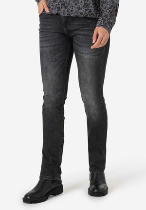 Dunkelblaue Jeans im Straight-Leg-Schnitt mit dezenten Falten und mittlerem Waschgang. Kombiniert mit schwarzen, klobigen Stiefeletten.