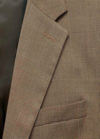 Blazer marrone con motivo a quadri, realizzato in un tessuto testurizzato che presenta piccoli quadretti. Dettaglio di cucitura sulla rever e una tasca singola.