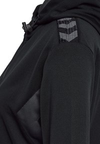 Zwarte sportieve hoodie met een gestructureerd oppervlak, voorzien van een capuchon, een ritskraag en contrasterende patronen op de schouder.