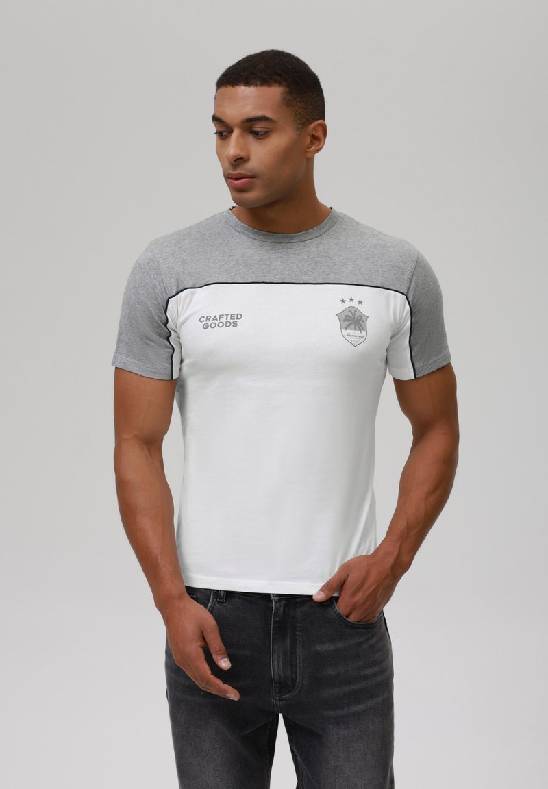 Men's short-sleeve t-shirt with grey sleeves and a white body, featuring a logo and text. Smooth cotton material, round neck design.