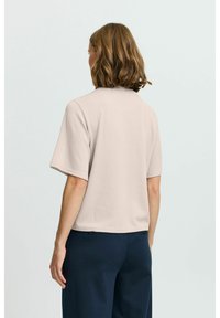 Korthåndet ribbet top i lys beige, med rund halsudskæring og afslappet pasform, parret med marineblå vide bukser.