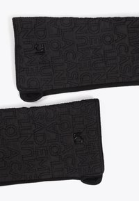 Černé prošívané látkové zápěstní nebo paže zahřívače s reliéfním písmem a černým akcentním logem. Měkký povrch s zaoblenými konci.