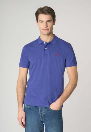 Polo a maniche corte in cotone viola intenso con una texture morbida, caratterizzato da un logo ricamato rosso sul petto e una abbottonatura.