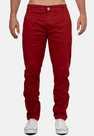 Rode katoenen broeken hebben een slim fit, voorkeppen en een knoopsluiting. Gecombineerd met witte sneakers voor contrast.