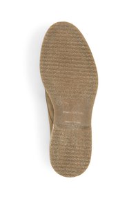 Semelle de chaussure beige en caoutchouc avec une surface texturée, en forme ovale, et de légères lignes de grip qui traversent horizontalement.