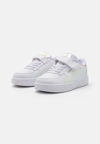 Baskets blanches en cuir avec une texture lisse, dotées d'une sangle velcro, d'un lacet à l'avant et d'accents latéraux irisés. Design décontracté.