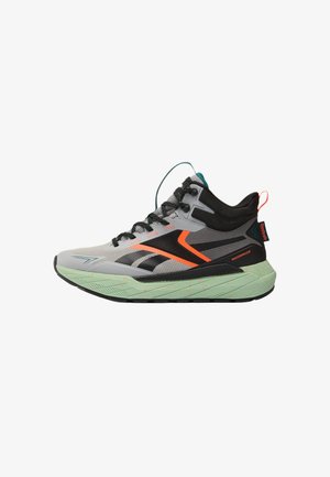 Sneaker impermeabile grigia e nera con dettagli arancioni, lacci neri e suola testurizzata verde chiaro.