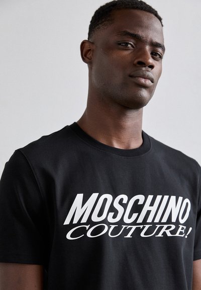 T-shirt in cotone nero con testo bianco audace che recita "MOSCHINO COUTURE!" Design a girocollo con maniche corte e texture liscia.