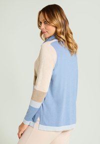 Lightweight sweater in shades of blue, beige, and light blue. Features a ribbed collar and side slits. Soft texture and relaxed fit.