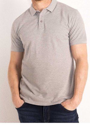 Homme portant un polo gris clair à manches courtes avec deux boutons, mains dans les poches d’un jean bleu foncé, montré du cou aux hanches.