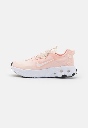 Baskets Nike rose clair avec logo swoosh blanc, semelle blanche texturée avec grips noirs et panneau en mesh au talon, vues de profil.