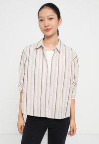 Camisa cor-de-rosa clara, com riscas verticais verdes e amarelas, corte descontraído, colarinho pontudo e mangas três quartos.